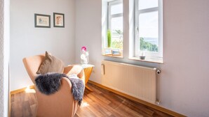 A cozy room with a wooden ceiling, a radiator, and two windows offering a view of greenery. - Wohnung in Battenberg nahe Winterberg Skigebiet (Battenberg)