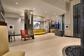 Een ruime lobby met een receptiebalie, zithoek en een modern design.