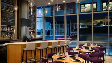 A bar area with a wooden counter, bar stools, and a menu board.
