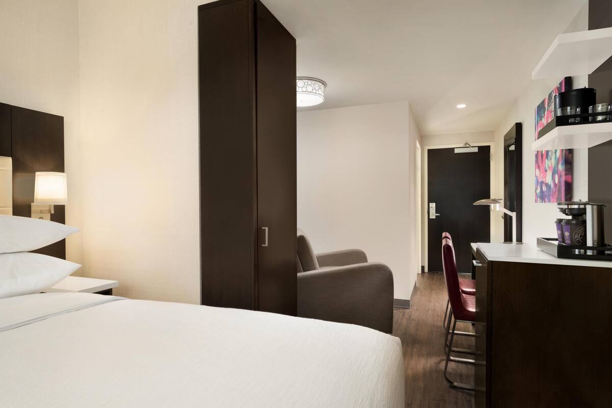 Une chambre d’hôtel équipée d’un lit, d’un bureau, d’une chaise et d’une kitchenette.