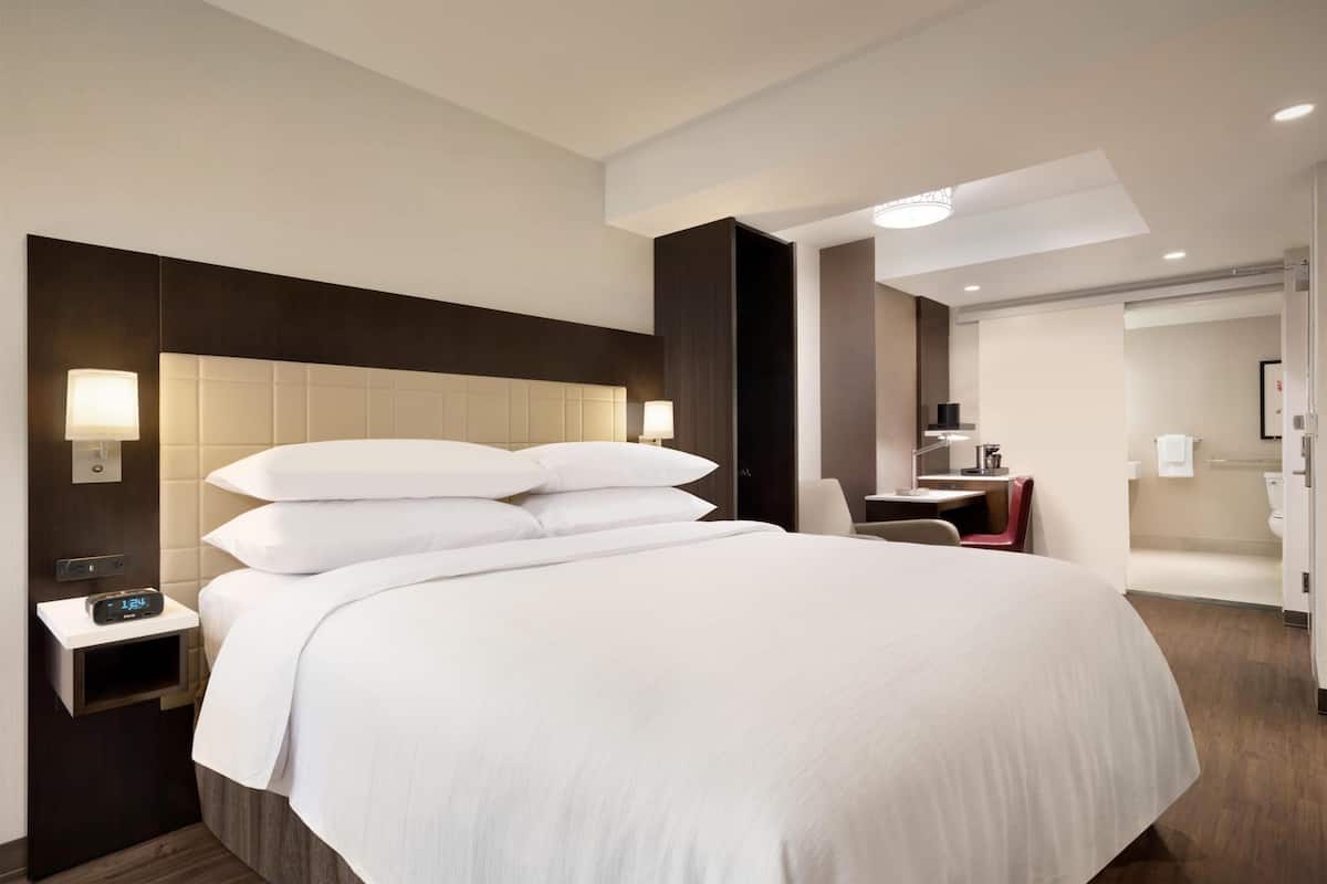 Une chambre d’hôtel avec un grand lit, des tables de chevet, un bureau et une salle de bain.