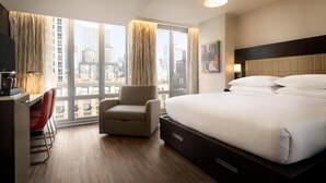 A hotel room with a bed, a desk, a chair, and a large window with a city view. - Embassy Suites by Hilton New York Manhattan Times Square (New York)