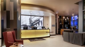 A modern hotel lobby with a reception desk, seating area, and a large window displaying a cityscape. - Embassy Suites by Hilton New York Manhattan Times Square (New York)