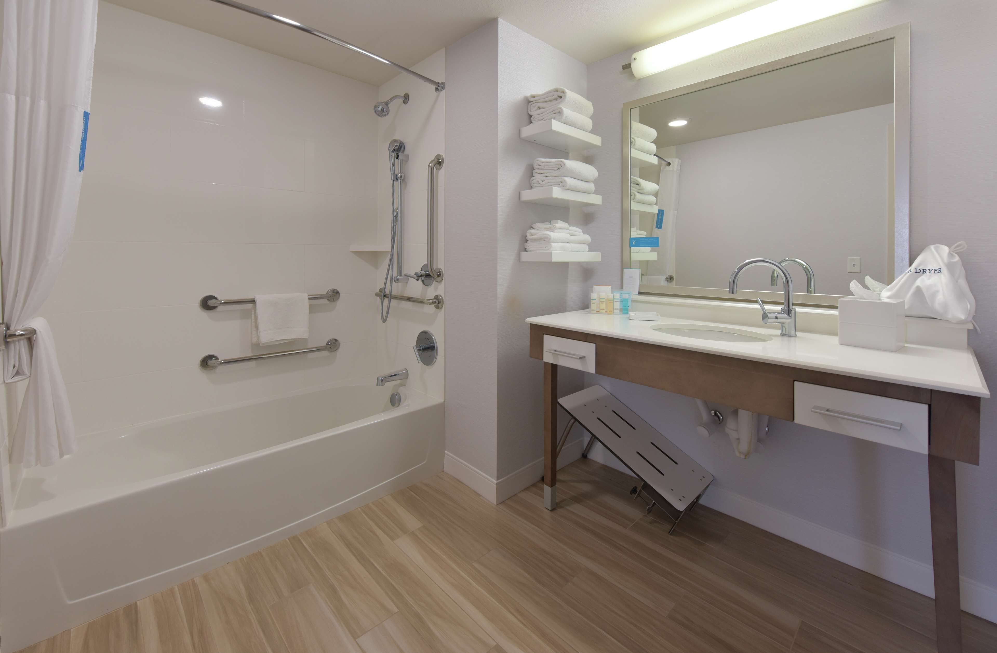 A modern bathroom with a bathtub, shower, and vanity with a mirror.