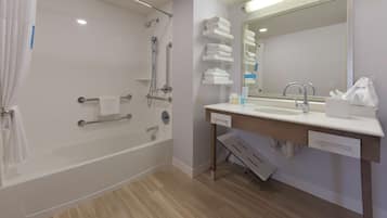 A modern bathroom with a bathtub, shower, and vanity with a mirror.