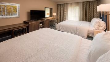 Quarto de hotel com duas camas, televisão, escrivaninha e micro-ondas.