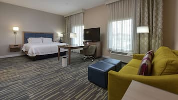 A hotel room with a bed, a desk, a television, a sofa, and a lamp.