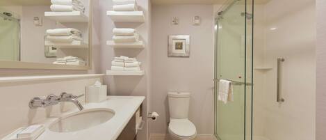 A modern bathroom with a glass-enclosed shower, a white sink, and a toilet.