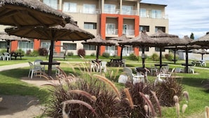 A hotel with multiple balconies, outdoor seating areas, and thatched umbrellas. - Howard Johnson Plaza Villa Carlos Paz (Villa Carlos Paz)