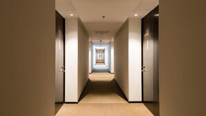 A hotel hallway with doors on both sides, a carpeted floor, and recessed lighting. - Howard Johnson Plaza Villa Carlos Paz (Villa Carlos Paz)