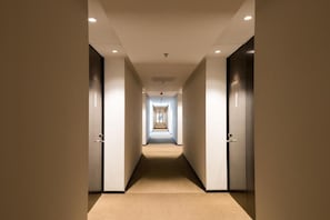 A hotel hallway with doors on both sides, a carpeted floor, and recessed lighting. - Howard Johnson Plaza Villa Carlos Paz (Villa Carlos Paz)