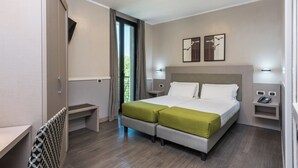 Ein modernes Hotelzimmer mit Doppelbett, Schreibtisch, Stuhl und Blick ins Freie.