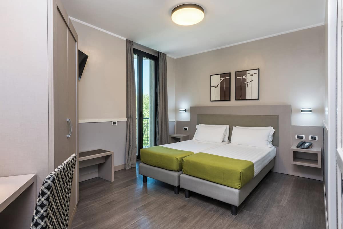 Ett modernt hotellrum med en dubbelsäng, ett skrivbord, en stol och utsikt över omgivningarna.