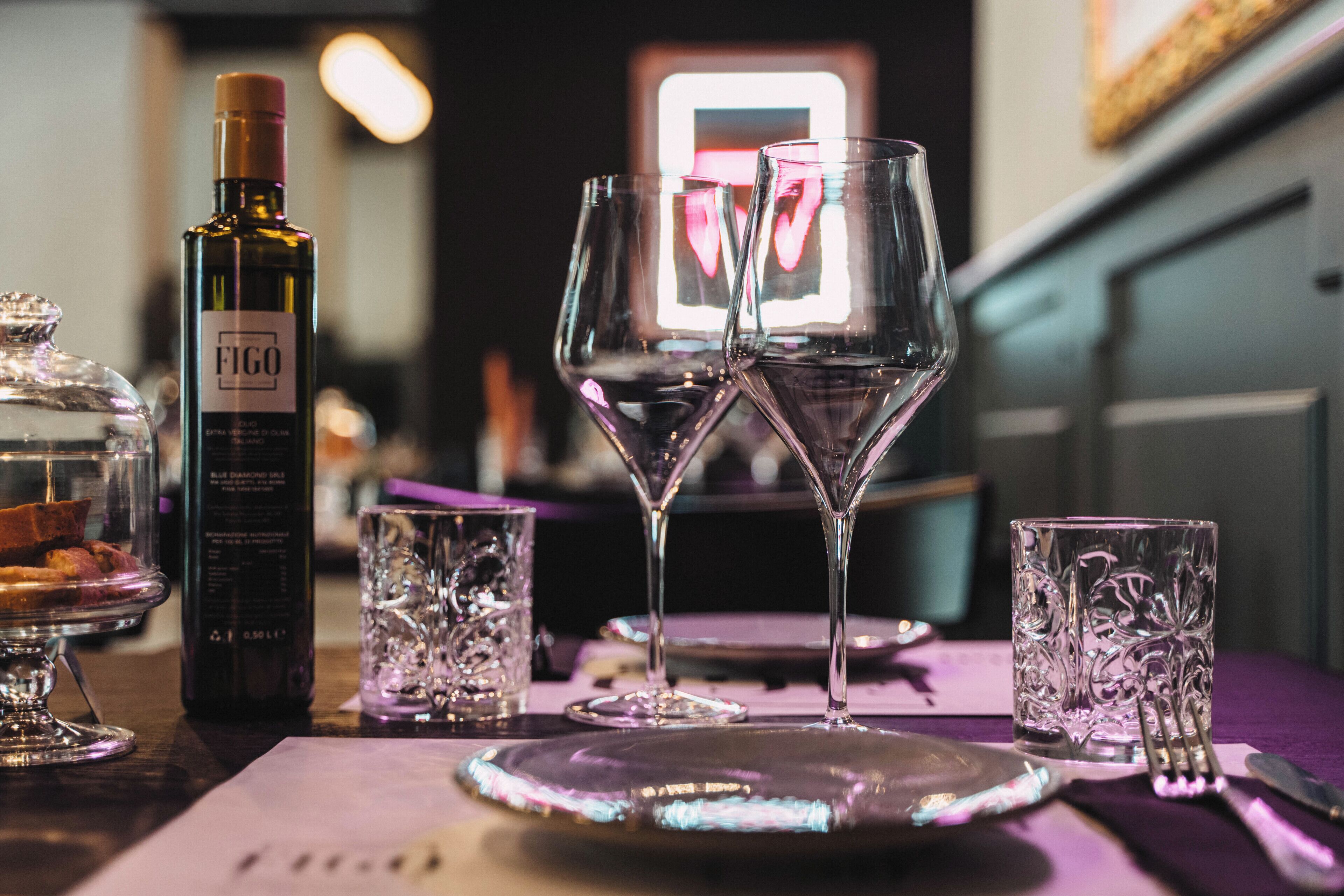 Une table dressée avec une bouteille de vin Figo, deux verres à vin et un verre à dessert.