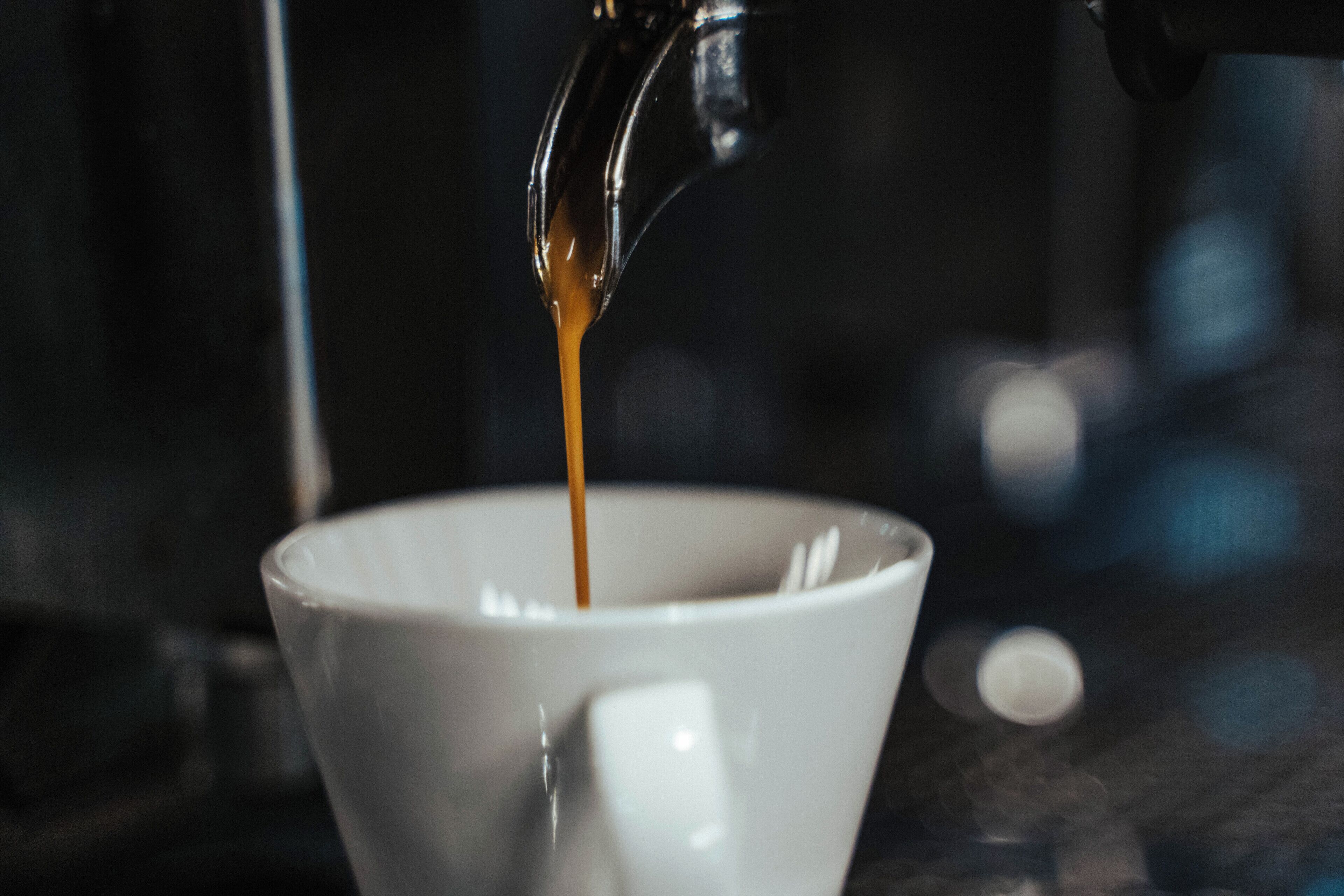 Koffie wordt van een koffiemachine in een kopje gegoten.