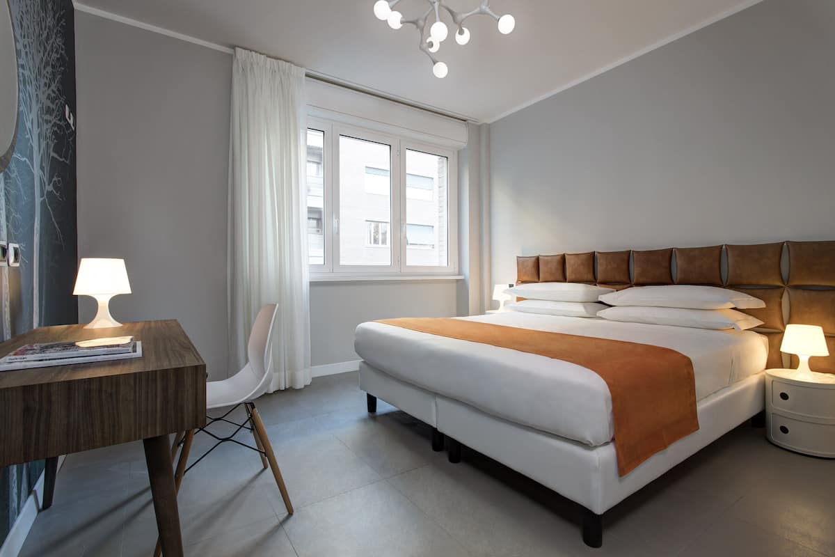Ett modernt hotellrum med en stor säng, ett skrivbord och en stol.
