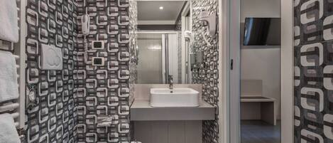 A modern bathroom with a patterned wall, a toilet, a sink, and a mirror.