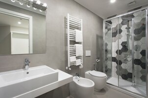 Et moderne badeværelse med stor vask, bidet, toilet og bruseniche.