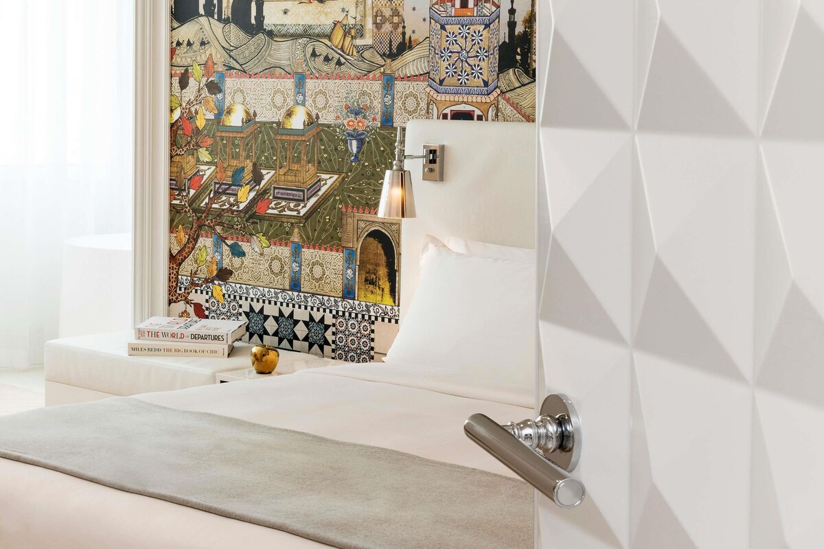 A bathroom with a white sink, a decorative tile backsplash, and a door with a geometric pattern.