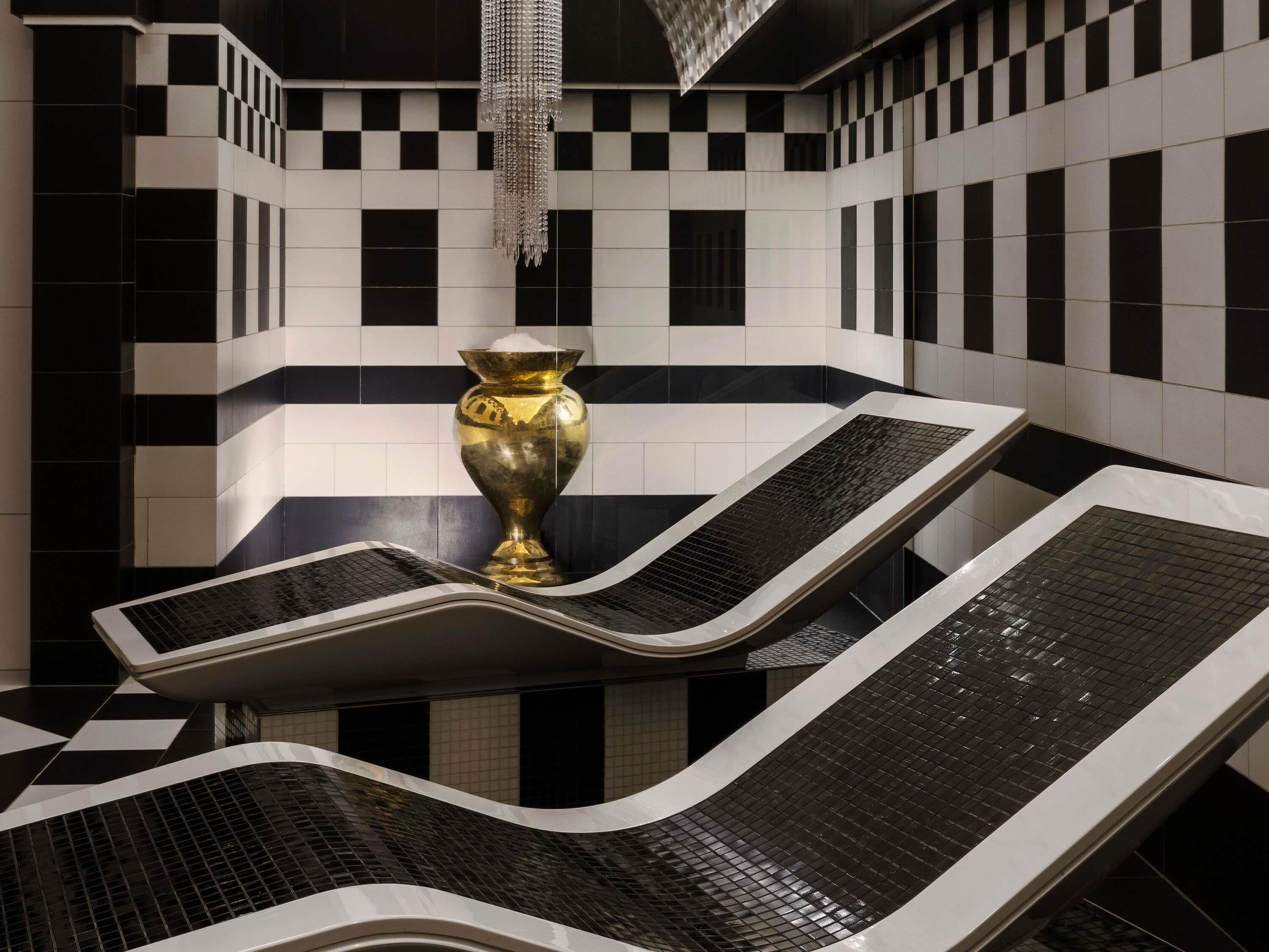 A checkered tiled wall, a gold vase, and a water feature.
