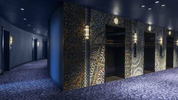 Un pasillo con alfombra estampada, paredes de azulejos e iluminación empotrada.