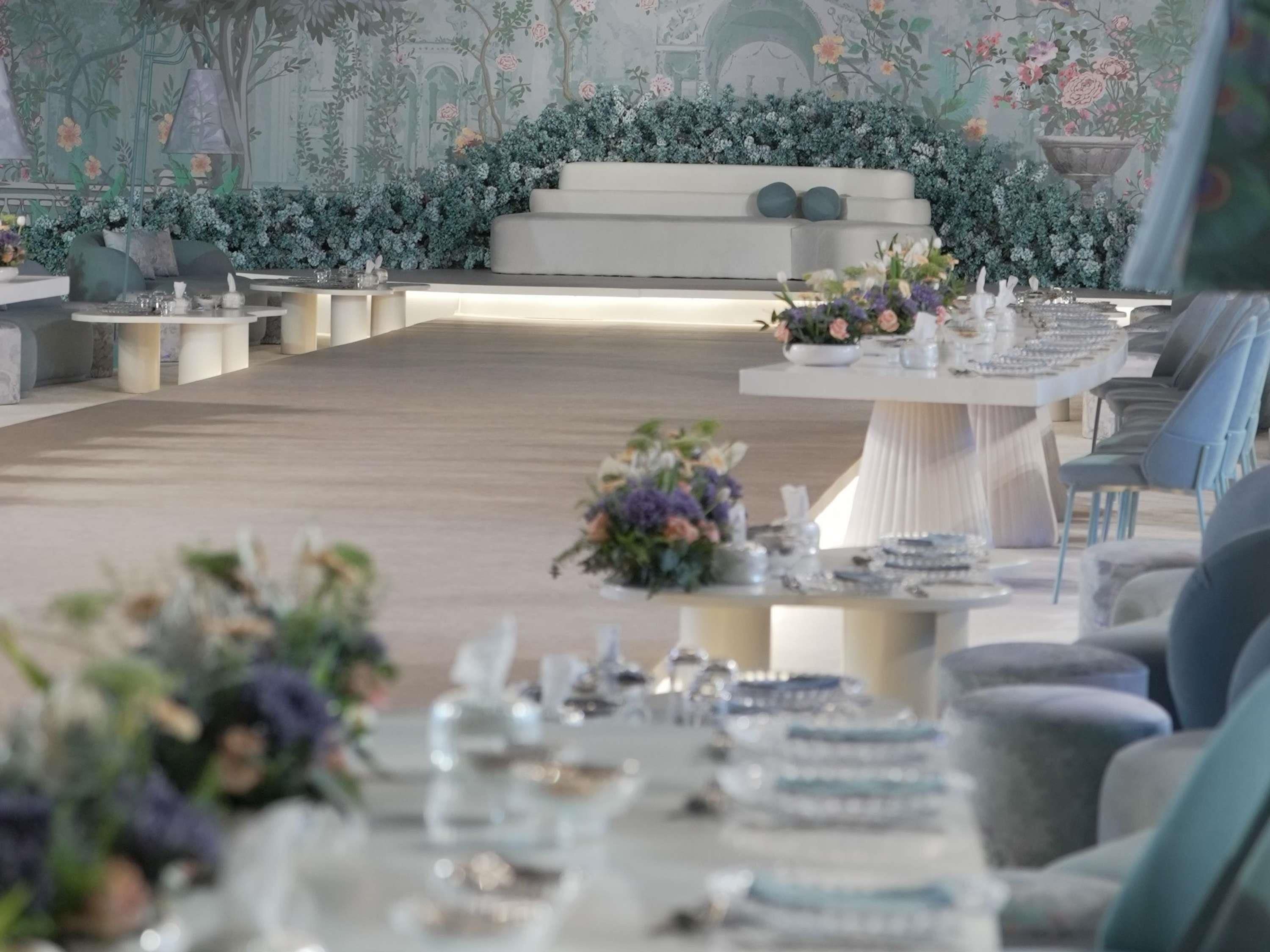 A formal dining area with a long table, chairs, and floral centerpieces.