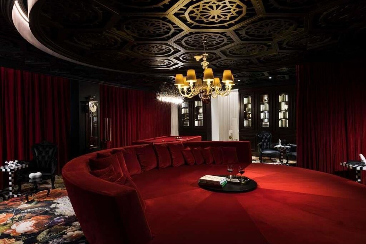 A room with a red carpet, a round table, and a chandelier.