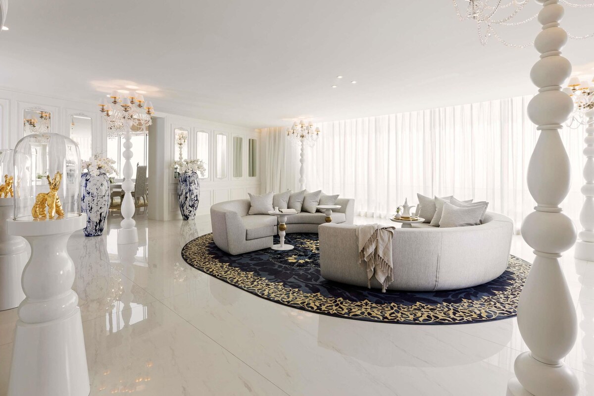 A spacious living room with a round coffee table, two sofas, and a chandelier.