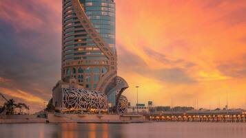 A modern building with a unique architectural design, featuring a prominent tower and a curved structure with intricate patterns.