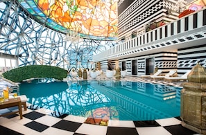 A luxurious indoor pool area with a geometric ceiling design, checkered floor, and lounge chairs. - Mondrian Doha (Doha)
