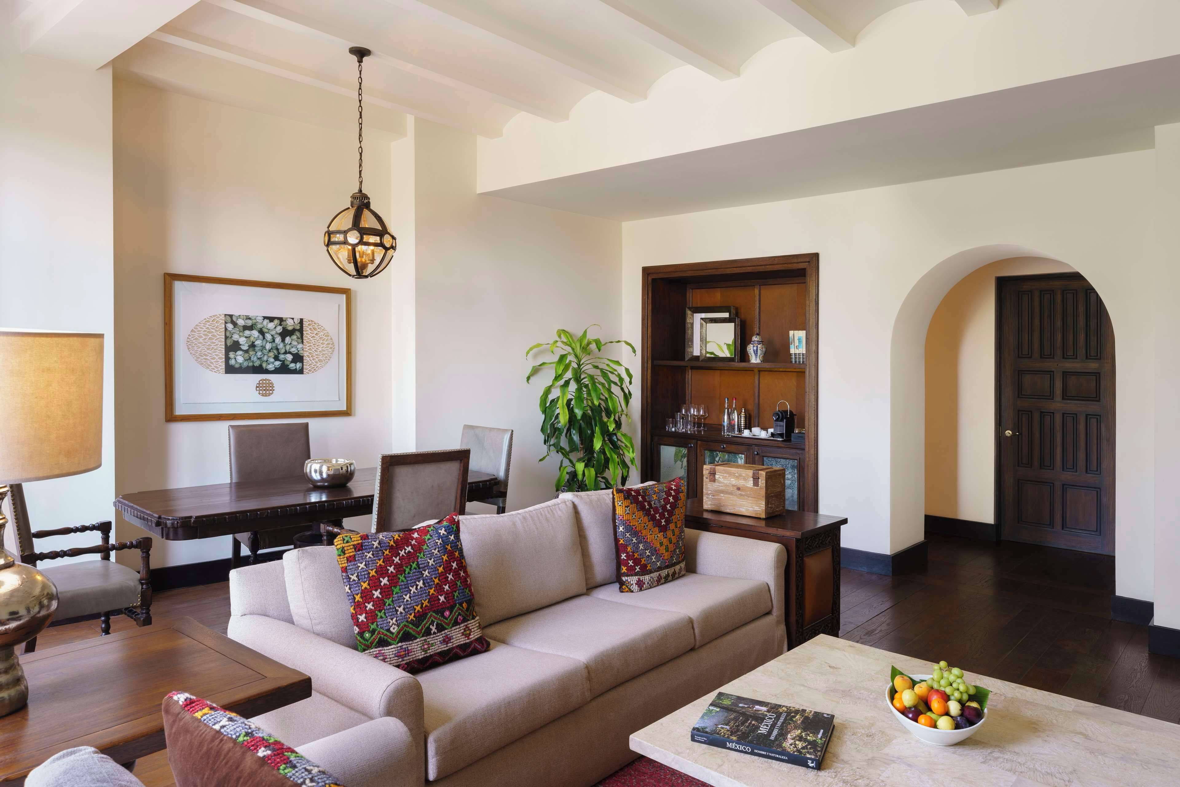 A living room with a sofa, coffee table, and a dining area with a table and chairs.