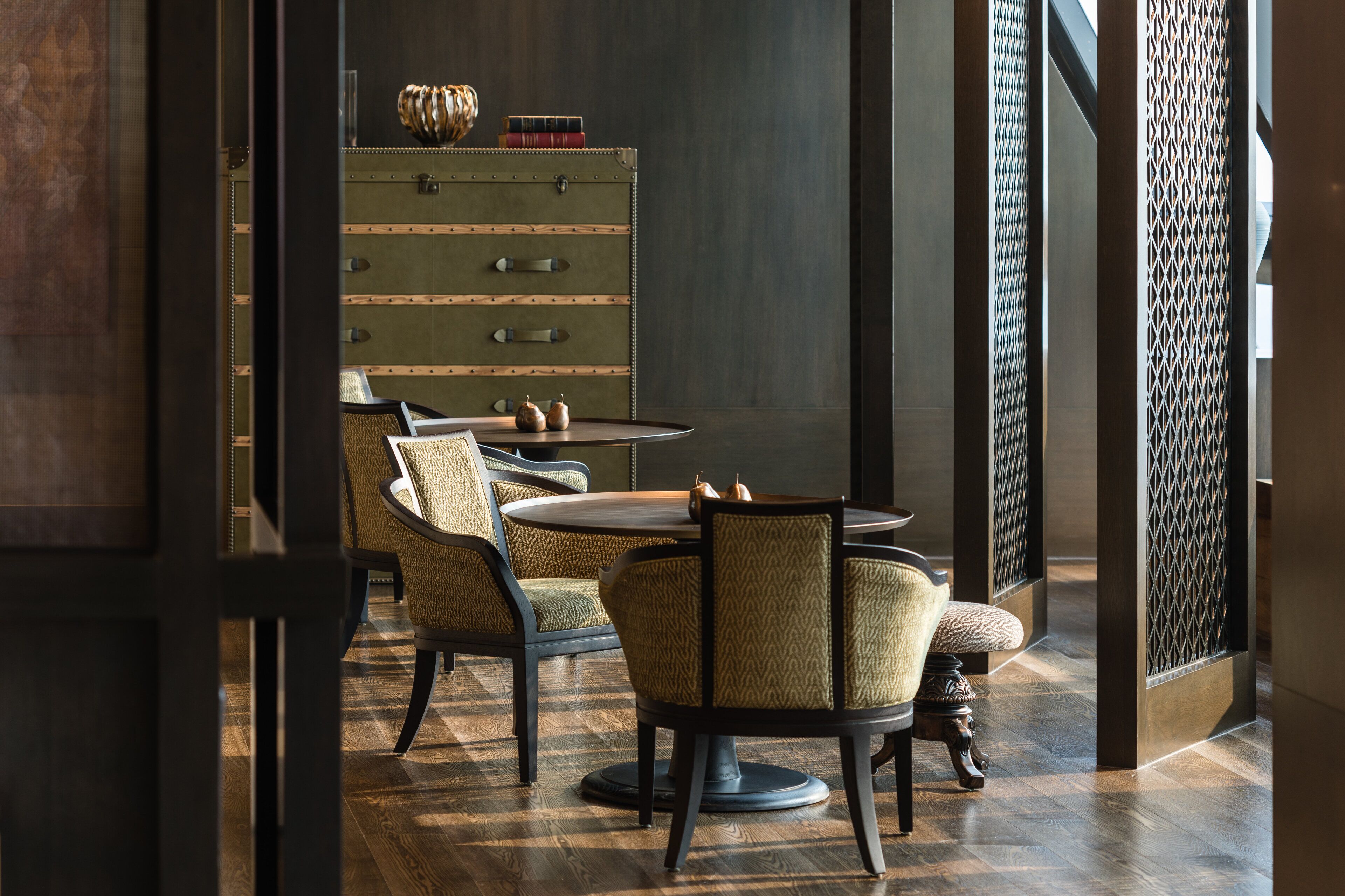 A dining area with a round table, two chairs, and a vintage-style chest of drawers.