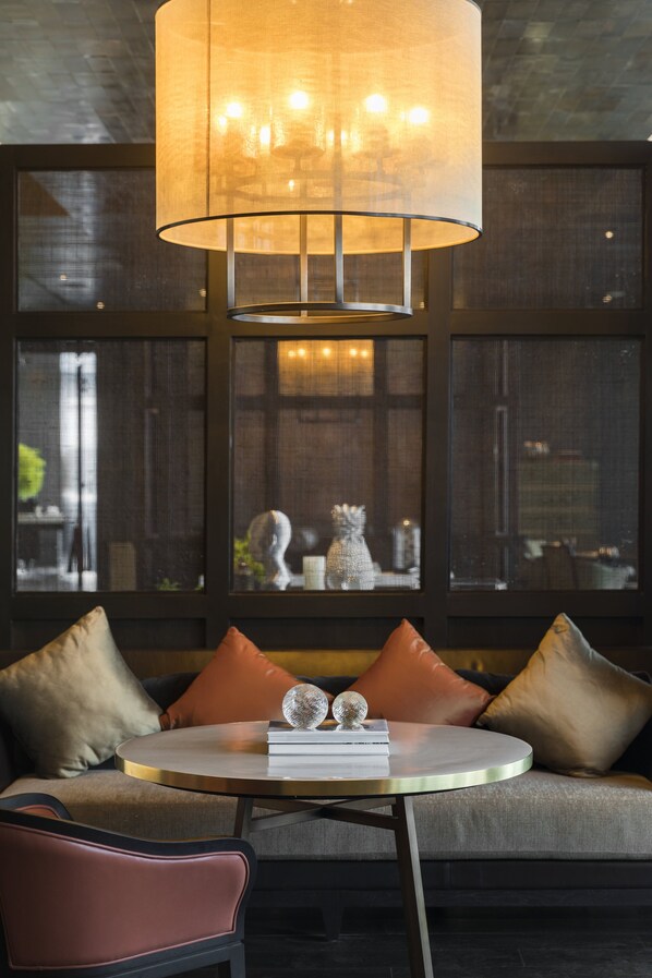 A modern interior with a round table, leather sofa, and a large hanging lamp. - Rosewood Phnom Penh (Phnom Penh)