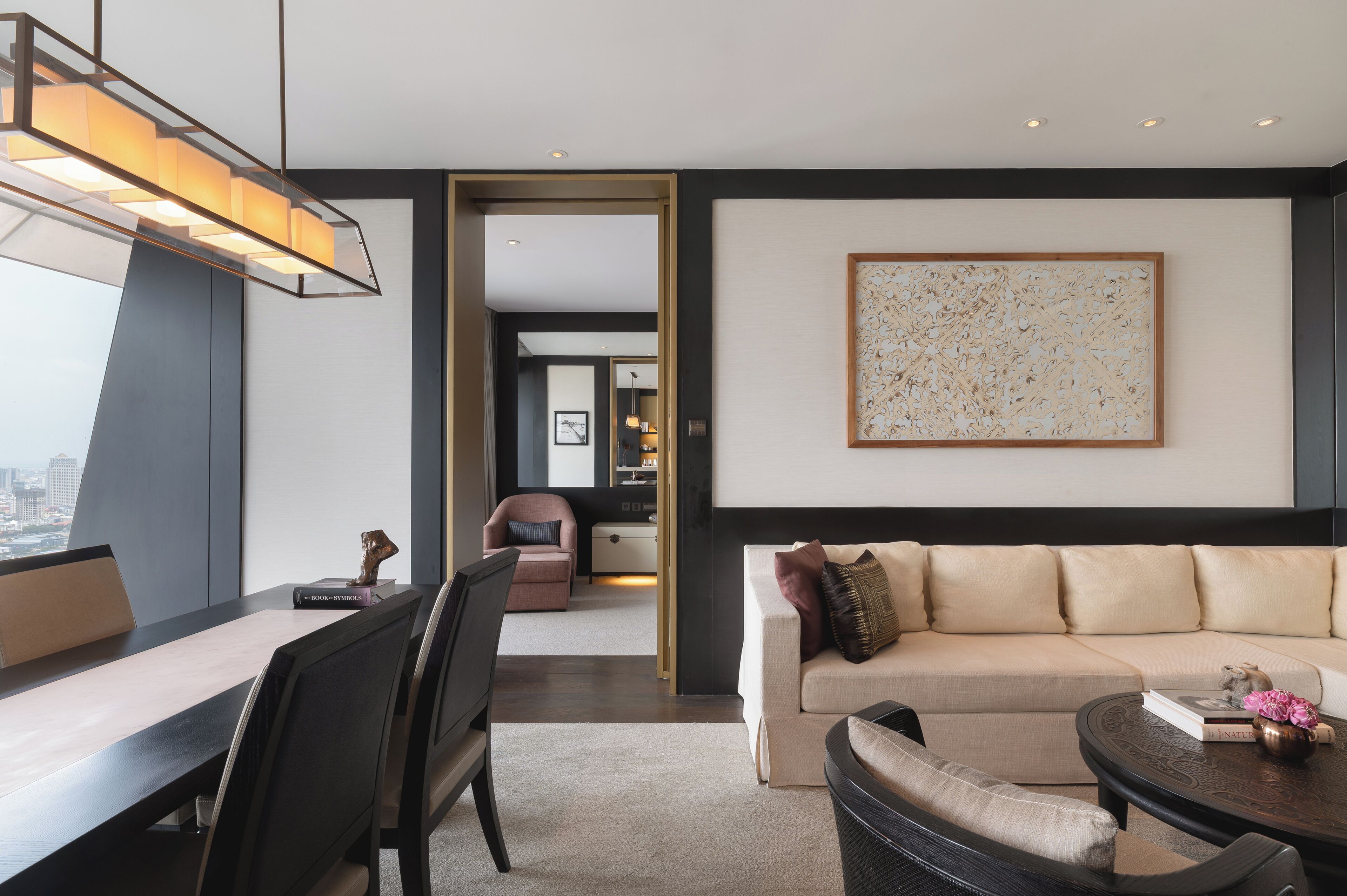 A modern living room with a sofa, a coffee table, and a dining area with chairs and a table.