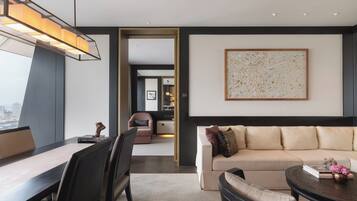 A modern living room with a sofa, a coffee table, and a dining area with chairs and a table.