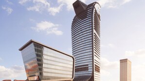 Un edificio moderno con fachada curva y una torre alta y cilíndrica.
