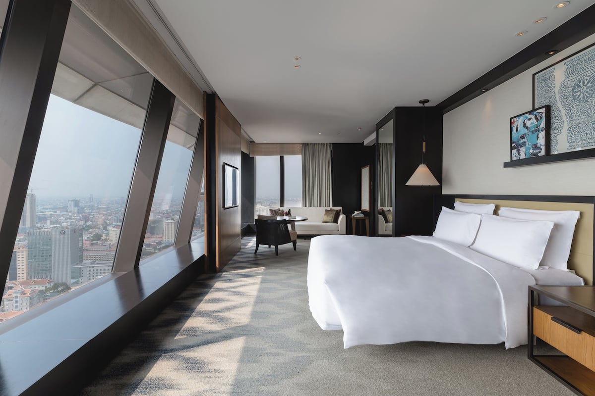 Une chambre d’hôtel moderne, dotée d’un grand lit, d’un bureau et offrant une vue sur la ville.