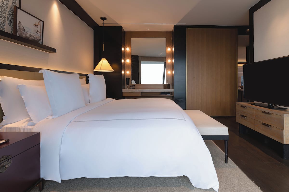 Une chambre d’hôtel moderne avec un grand lit, des tables de chevet, une télévision et un miroir.