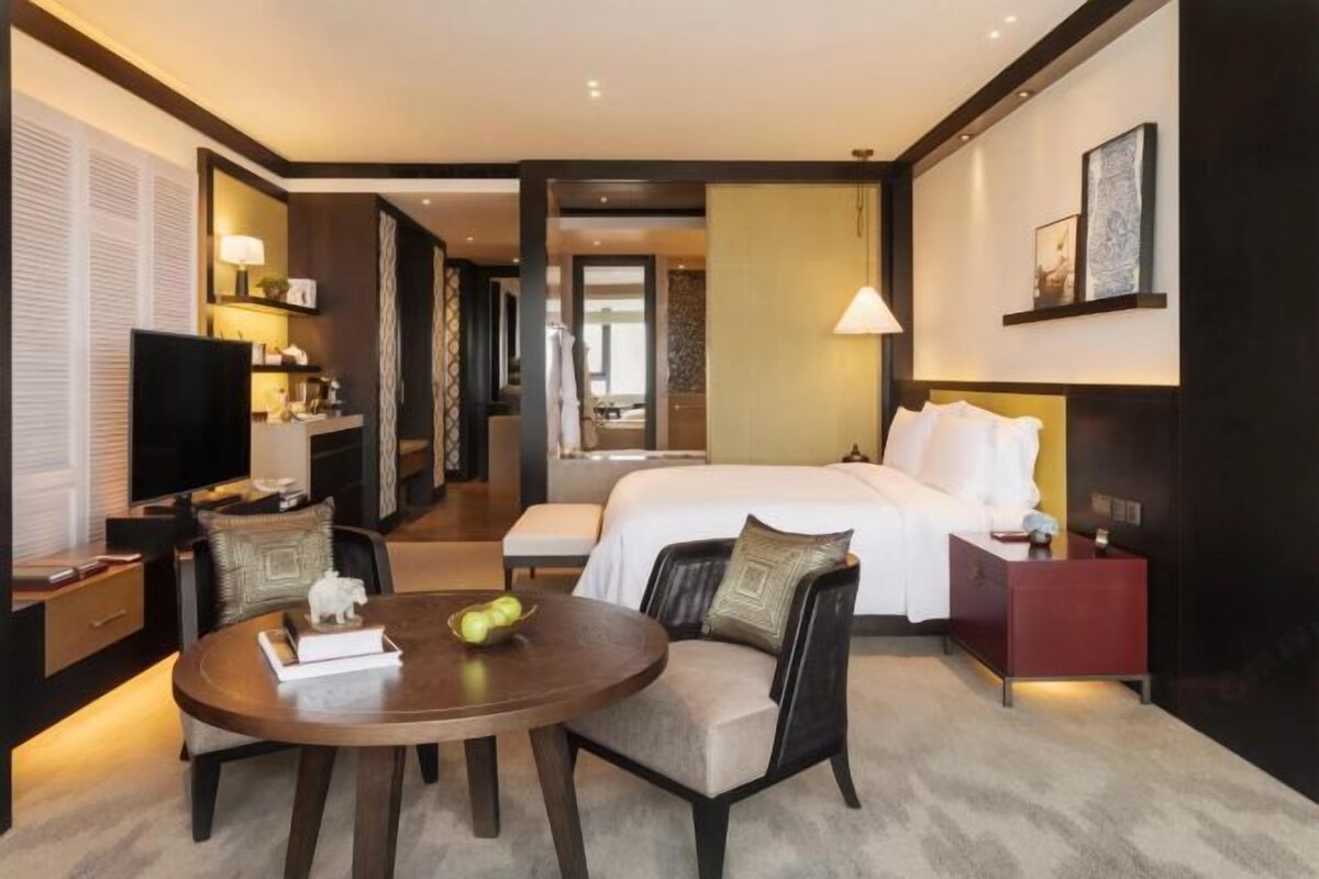 Une chambre d’hôtel comprenant un lit, une table de chevet, une lampe, une télévision et une table ronde avec des chaises.