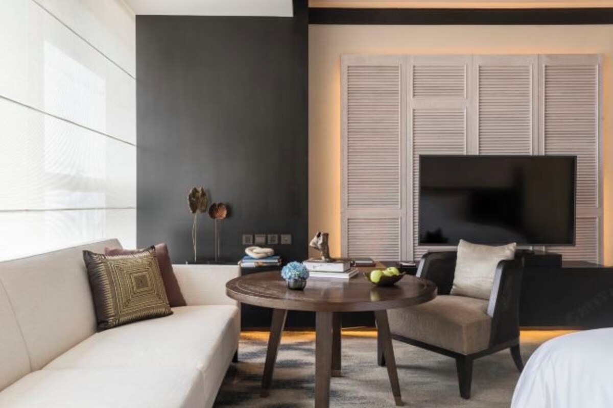 A modern hotel room with a sofa, a round table, and a TV.