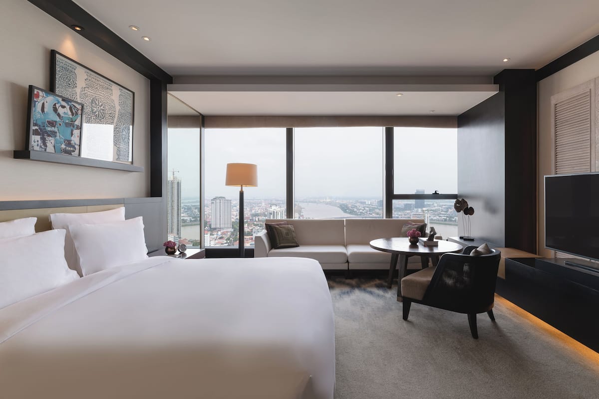Une chambre d’hôtel avec un grand lit, un canapé, une table à manger, une télévision et une vue sur la ville.