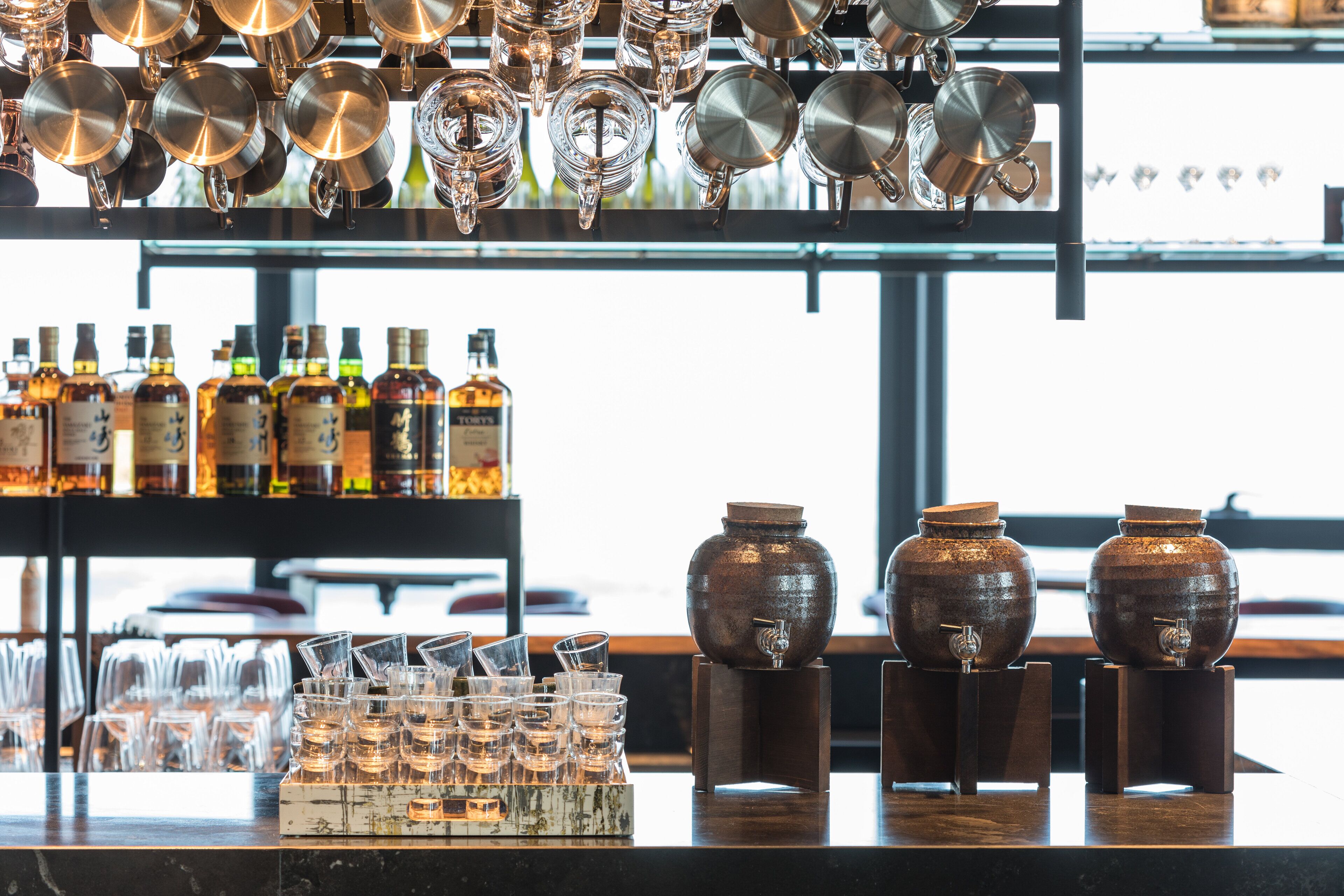 A bar area with various bottles, glasses, and metalware.