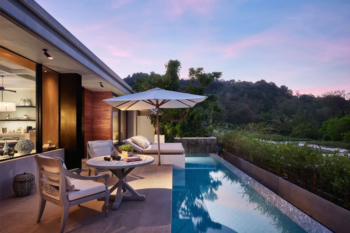 A modern outdoor pool area with a lounge chair, a table, and an umbrella.