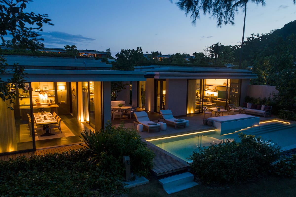 A modern house with a swimming pool, glass-enclosed rooms, and outdoor seating.