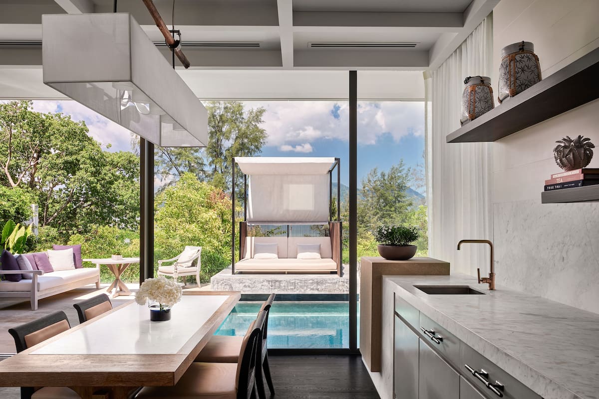 A modern kitchen with a marble countertop, a built-in sink, and a dining area with a pool view.