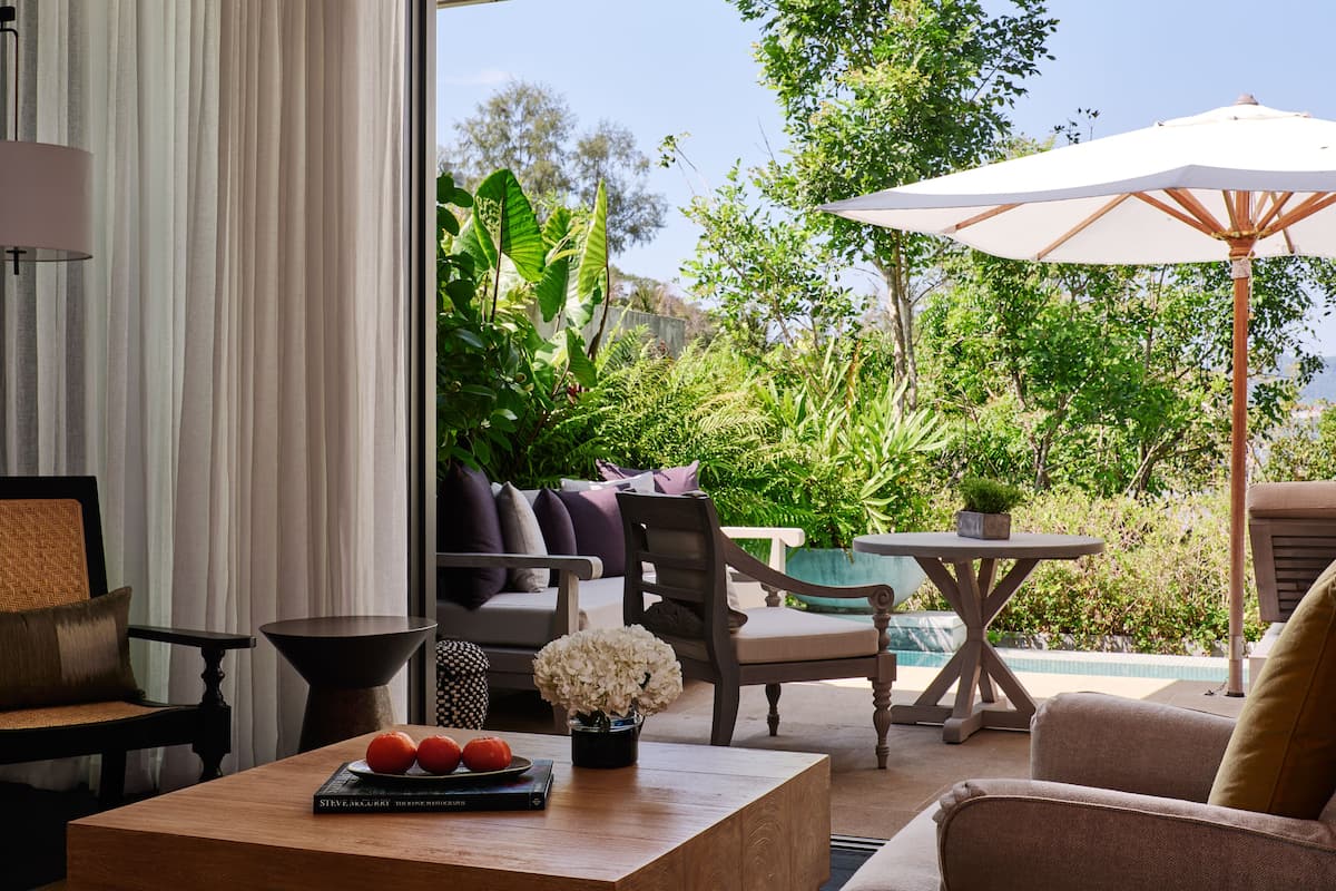 A modern outdoor seating area with a view of lush greenery and a pool.