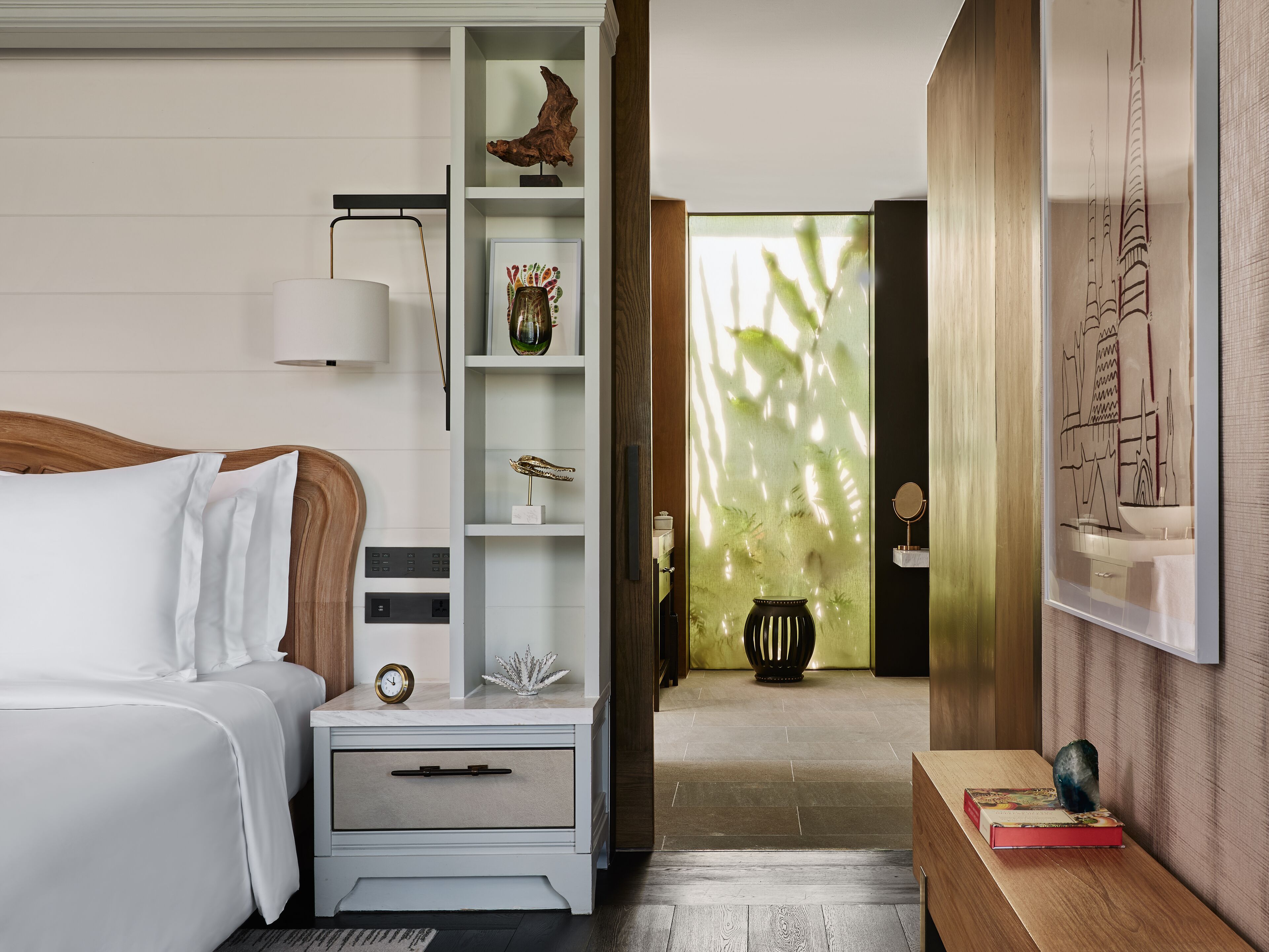 A modern bedroom with a bed, nightstand, and a shelf with decorative items.