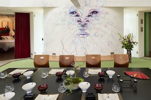A conference room with a large table set for a meeting, a decorative wall mural, and a view into a bedroom. - House of Time - Fancy Suite Vienna (Vienna)