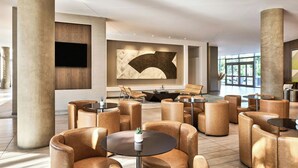 Eine geräumige Lobby mit Ledersitzmöglichkeiten, einem großen Wand-Fernseher und einem modernen Kamin.