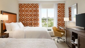 A hotel room with two beds, a desk, a chair, a TV, and a window with curtains. - Hampton Inn St. Albans (St. Albans)